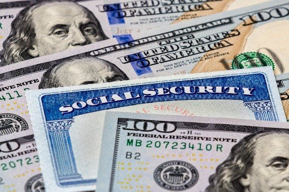 Social Security card laying in a pile of one hundred dollar bills. What you should know about survivor's benefits.